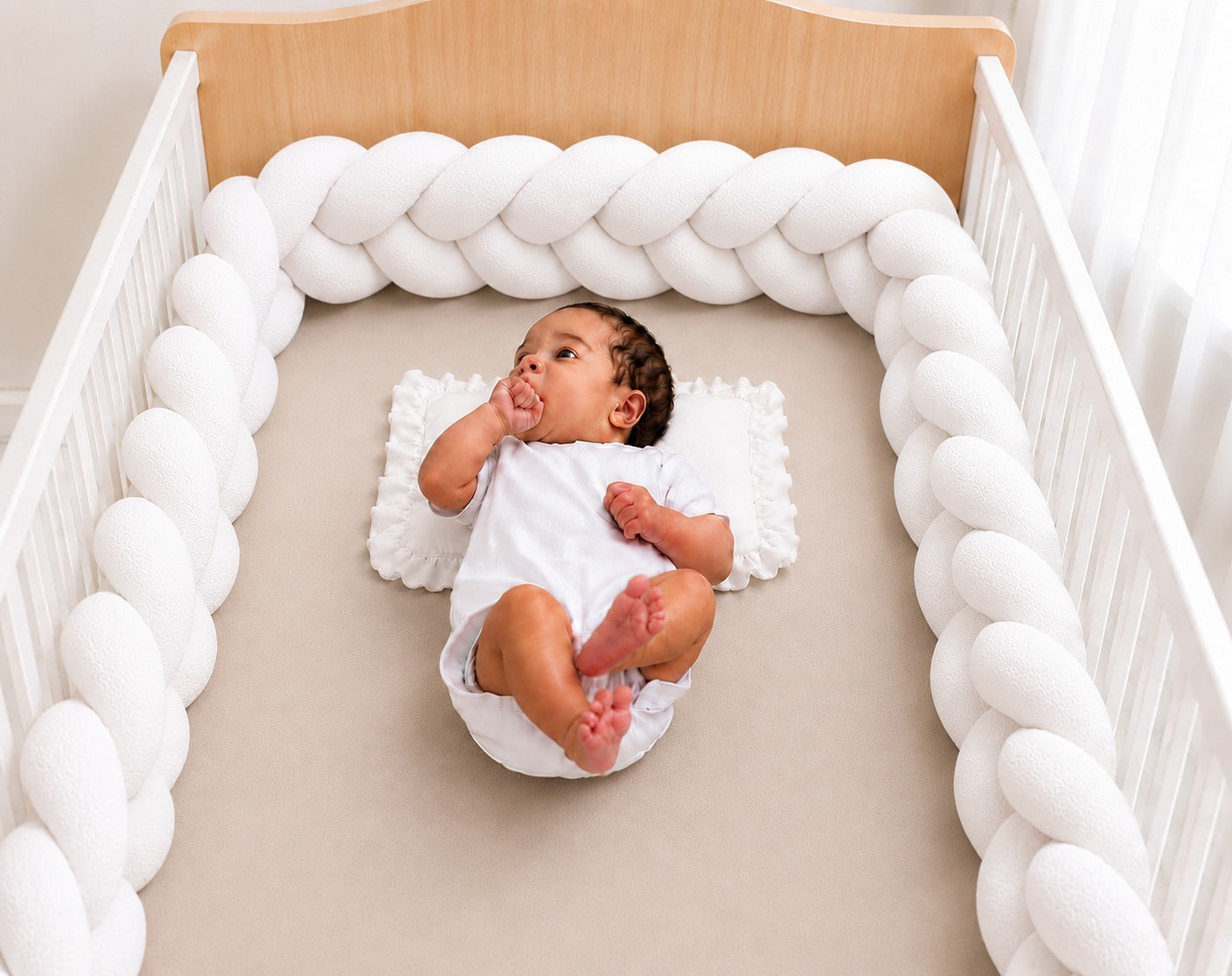 Tour de lit tressé blanc installé dans un berceau avec un bébé