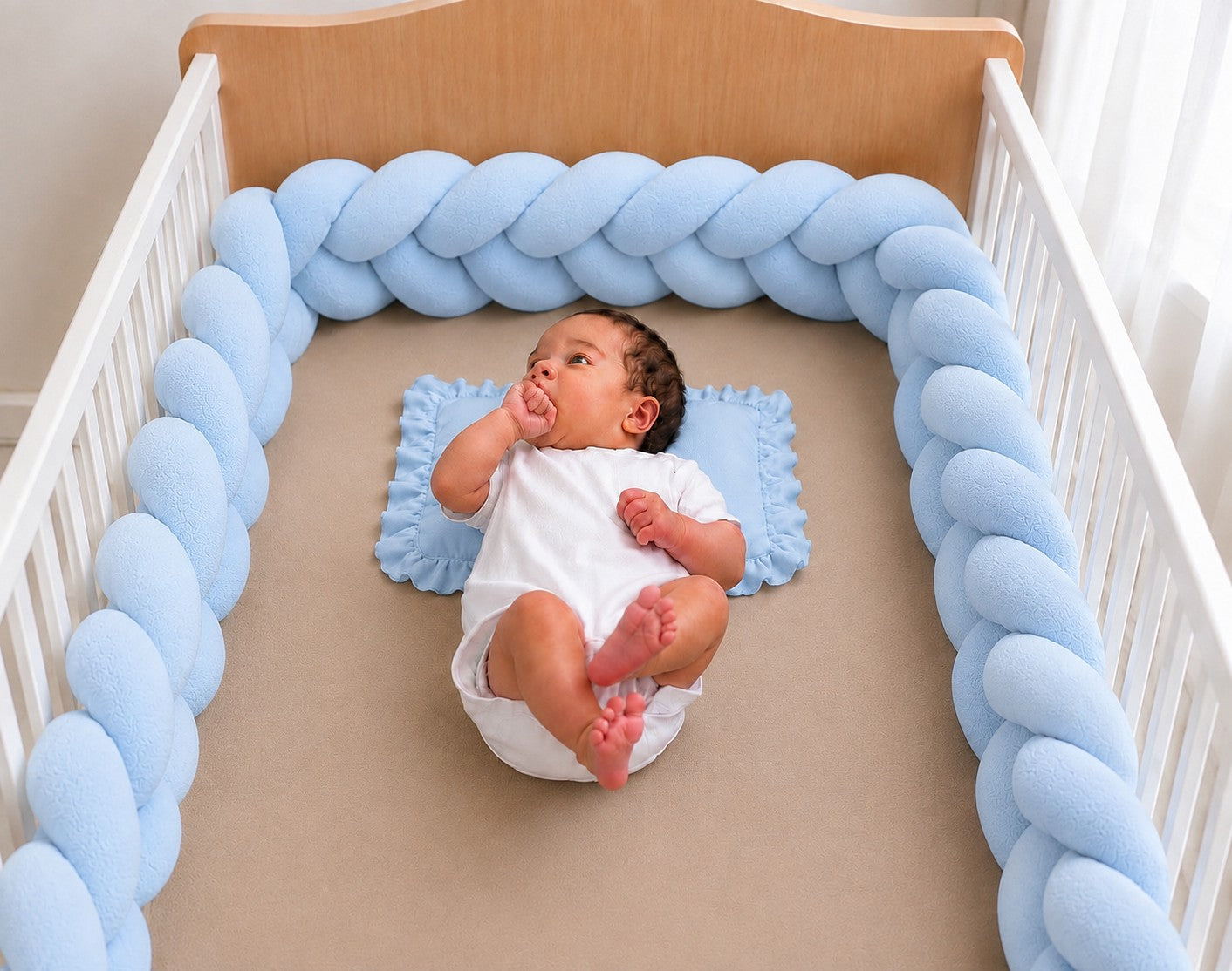 Tour de lit tressé bleu installé dans un lit bébé
