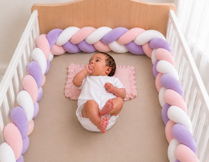 Tour de lit tressé rose blanc violet installé dans un lit bébé