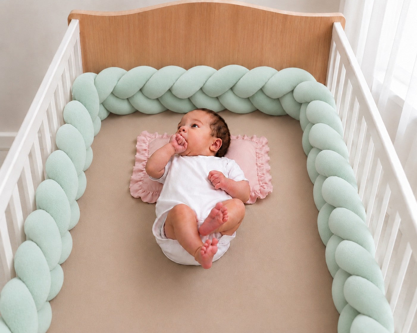 Tour de lit tressé bébé vert d’eau installé dans un lit à barreaux