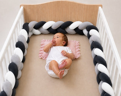 Tour de lit tressé pour bébé installé dans un lit à barreaux.
