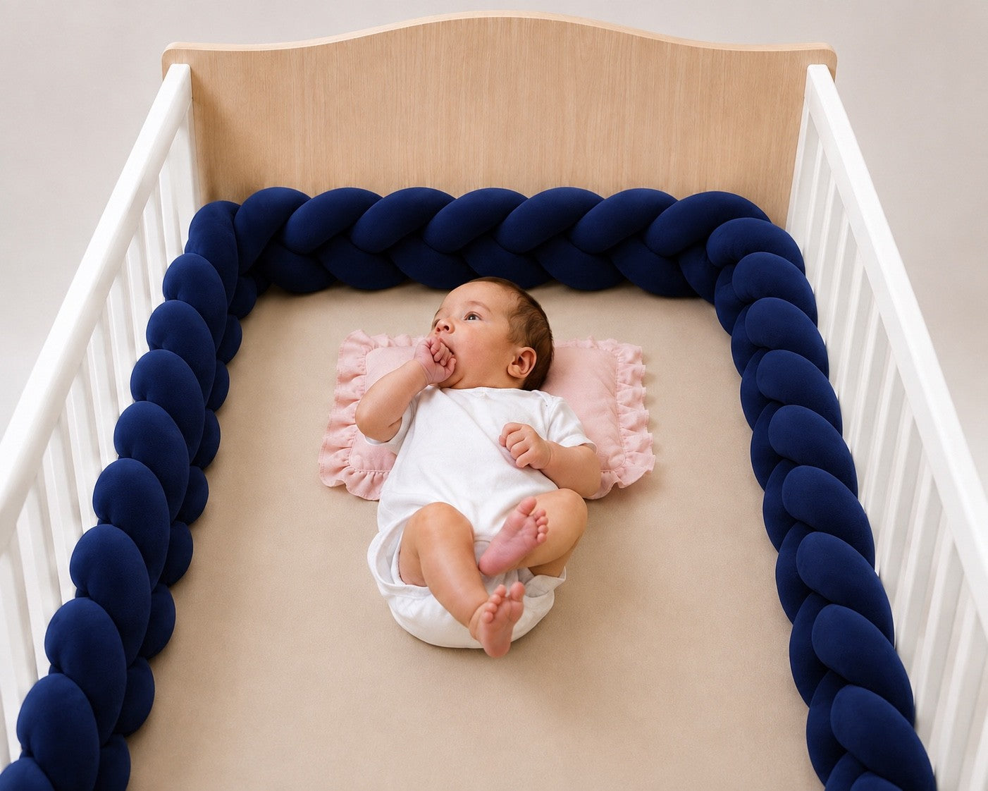 Tour de lit tressé bleu marine pour bébé dans un lit à barreaux