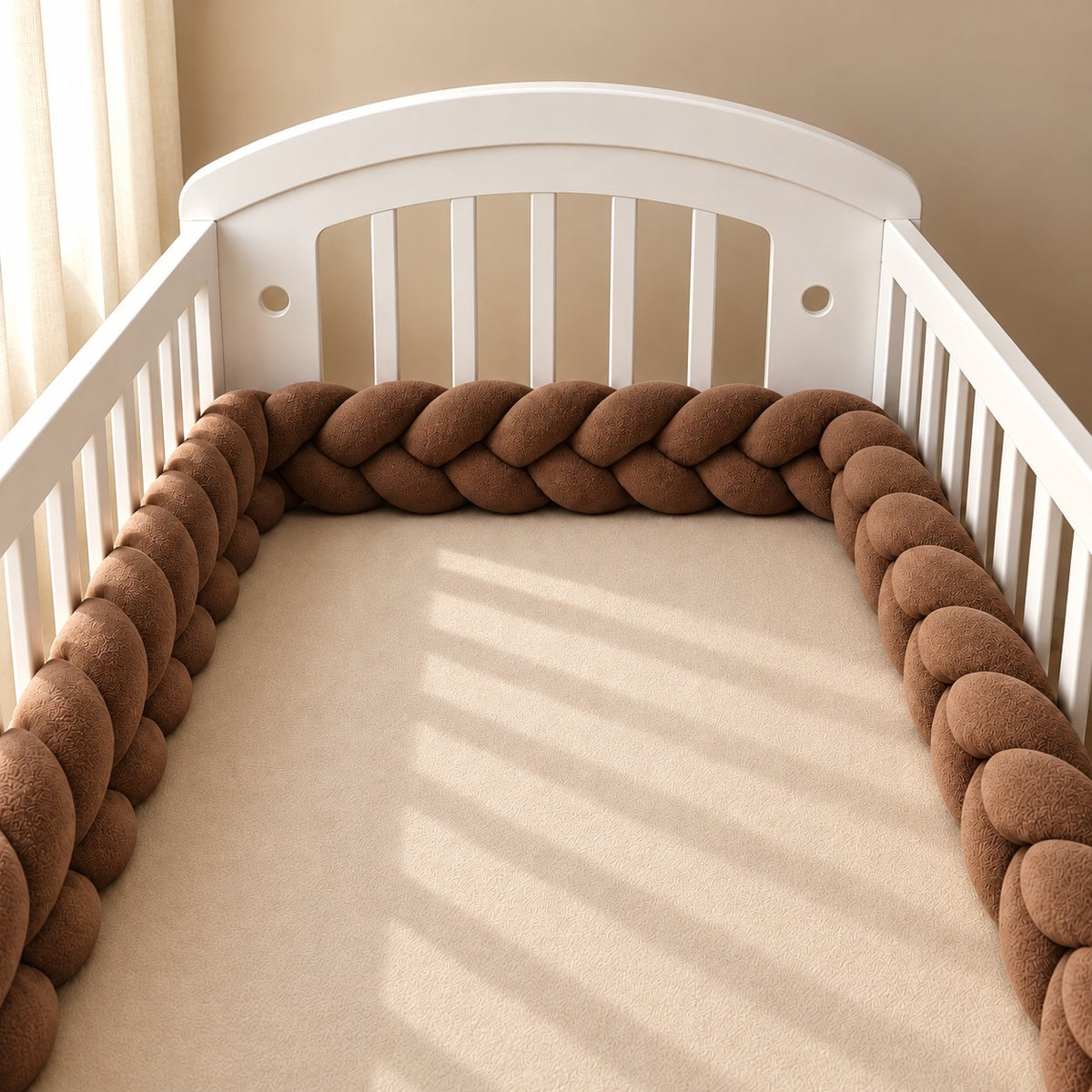 Tour de lit tressé marron installé autour du matelas d’un lit bébé blanc à barreaux.
